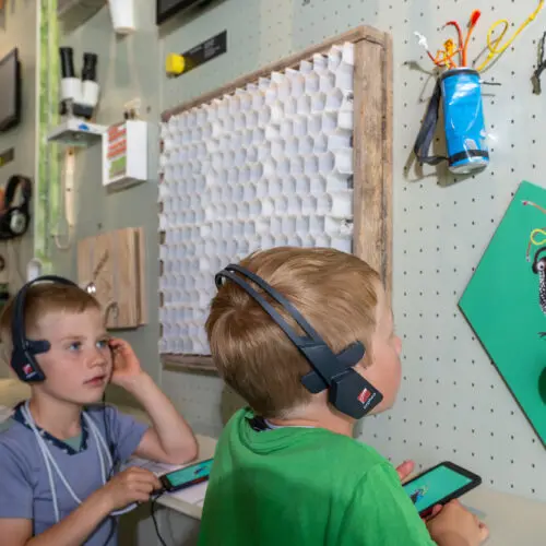 Kinder mit Audio-Guides bei einem Button der Geschichte von Ratsch und Furbina im Nationalparkzentrum