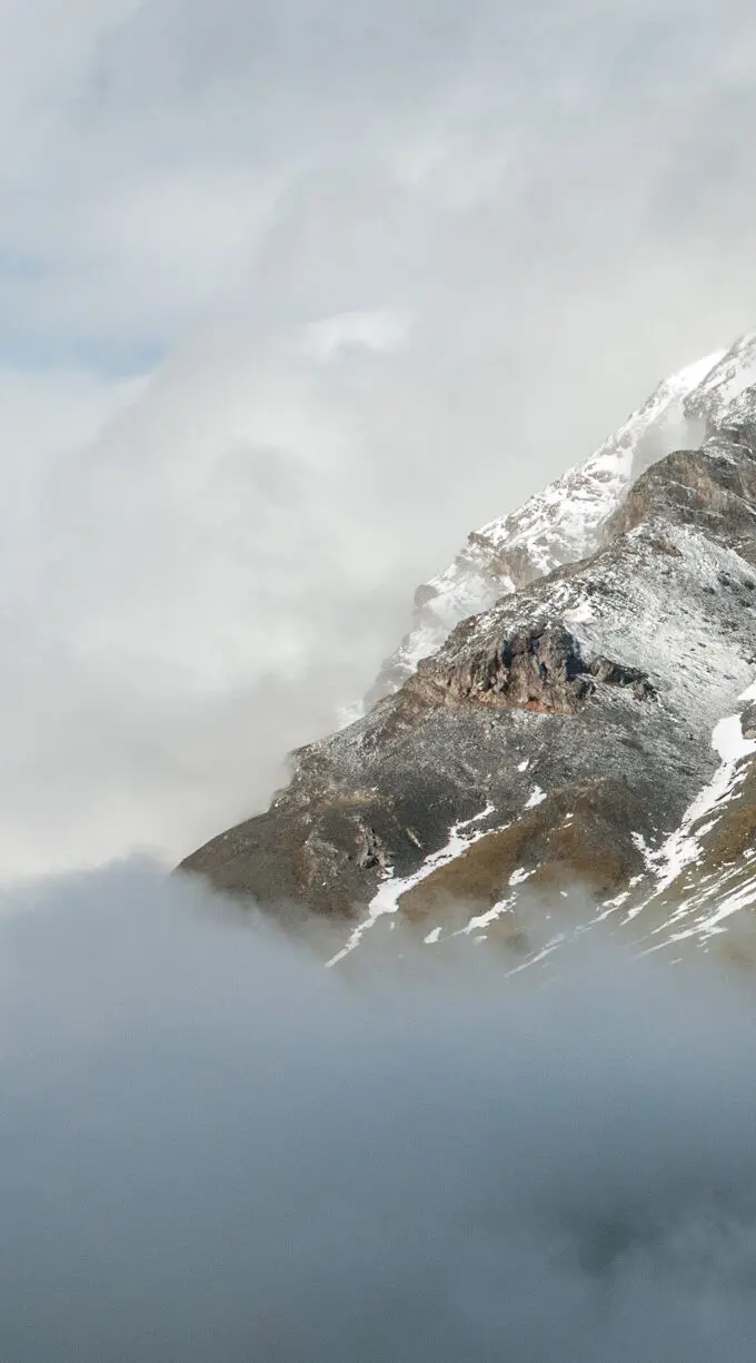 Wolkenstimmung mit Nebel und erstem Schnee an Felshängen