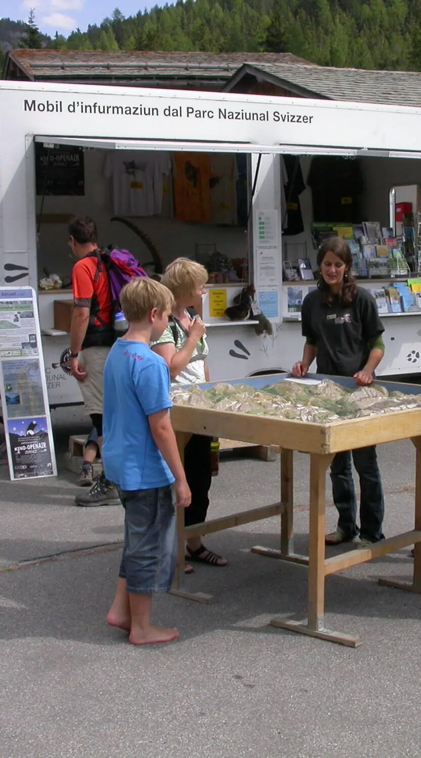 Vor dem Infomobil erläutert eine Park-Mitarbeiterin Gästen das etwa ein Quadratmeter grosse Relief des Nationalparks
