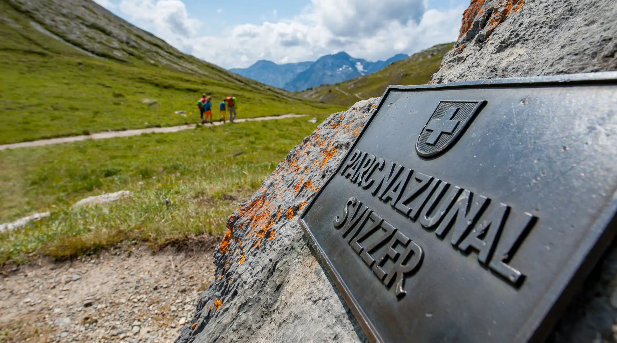 Metallschild Parc naziunal svizzer auf Steinbrocken am Wanderweg