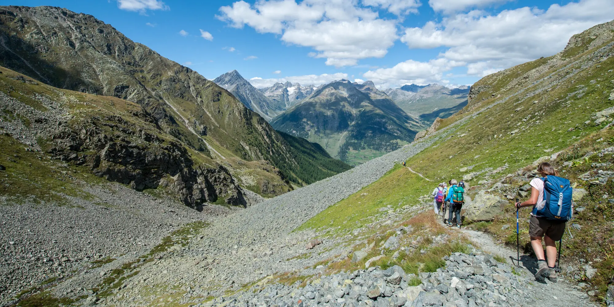 Wandernde auf dem Weg von Macun zur Alp Zeznina mit Blick ins Tal