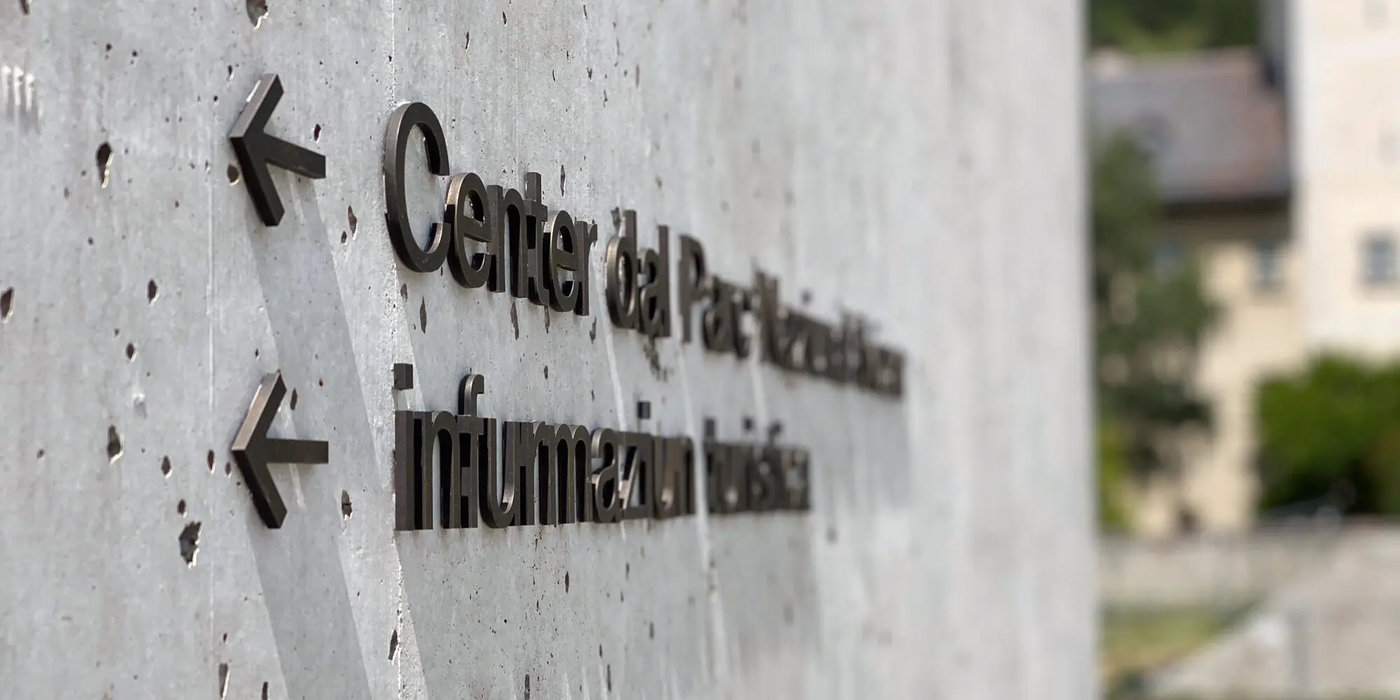 Romanische Beschriftung an der Aussenmauer des Center dal Parc / infurmaziun turistica