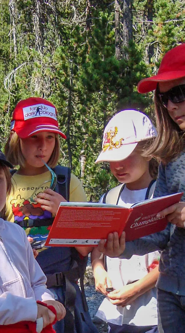 Kindergruppe studiert im Wald das Bilderbuch "Champlönch"
