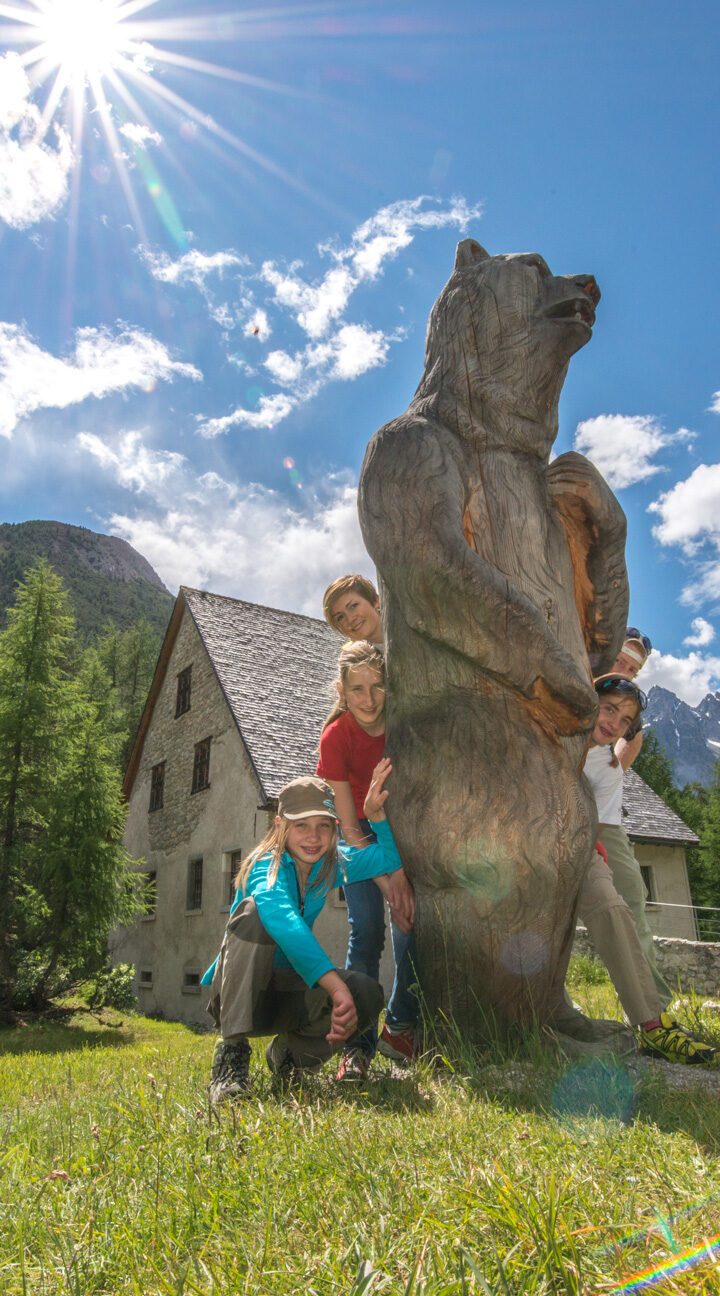Gäste mit der Holzskulptur eines Bären vor dem Museum Schmelzra