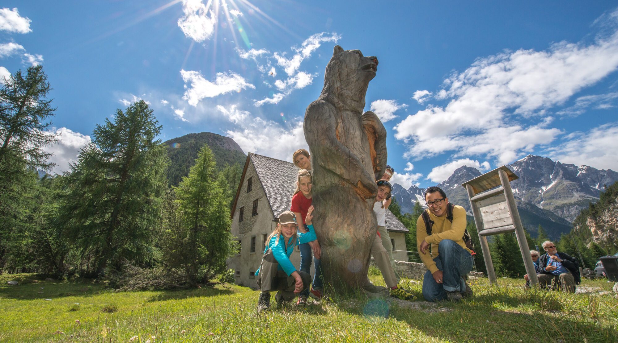 Gäste mit der Holzskulptur eines Bären vor dem Museum Schmelzra